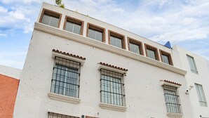 A multi-story building with a white facade, large windows, and a black entrance door. - Las Torres de Ugarte (Arequipa)