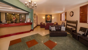 A lobby with a reception desk, seating area, and artwork. - Las Torres de Ugarte (Arequipa)
