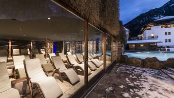 Zona de spa con tumbonas, piscina y vistas a la montaña.
