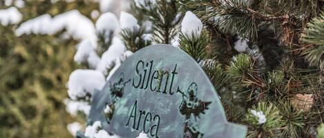 A sign labeled "Silent Area" on a metal post, surrounded by snow-covered pine branches.