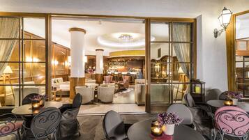 Un hall de hotel con zona de bar, arreglos de asientos y vistas a través de amplios ventanales.