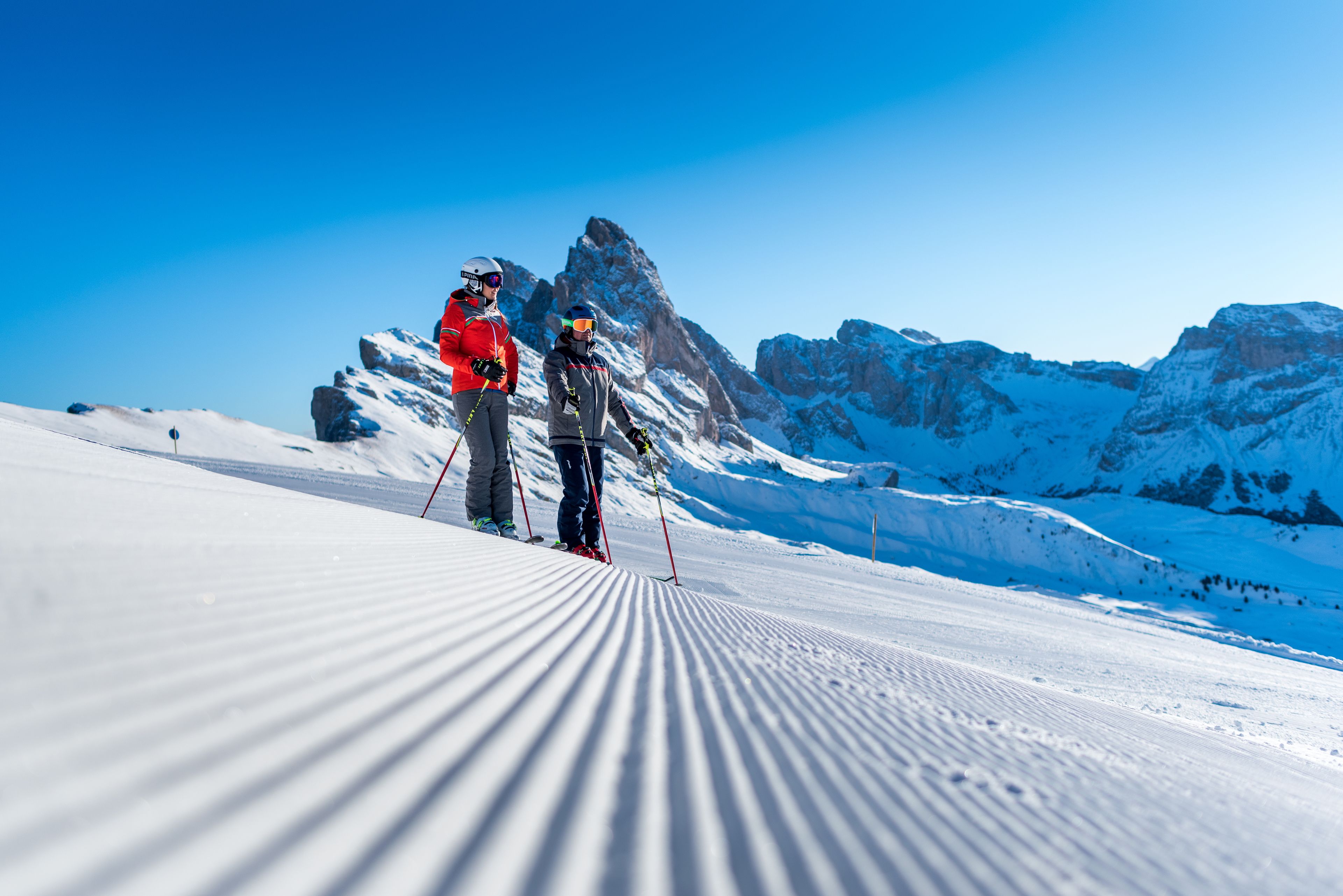 Une piste de ski enneigée avec deux skieurs au premier plan.