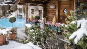 Una cabaña de madera con un letrero de sauna, piscina y plantas en macetas.