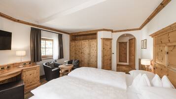 Habitación de hotel con una cama grande, un escritorio con lámpara, una silla, una mesita y armarios de madera.