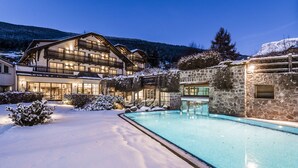 Un área de piscina exterior cubierta de nieve con un edificio de madera y una estructura de piedra.