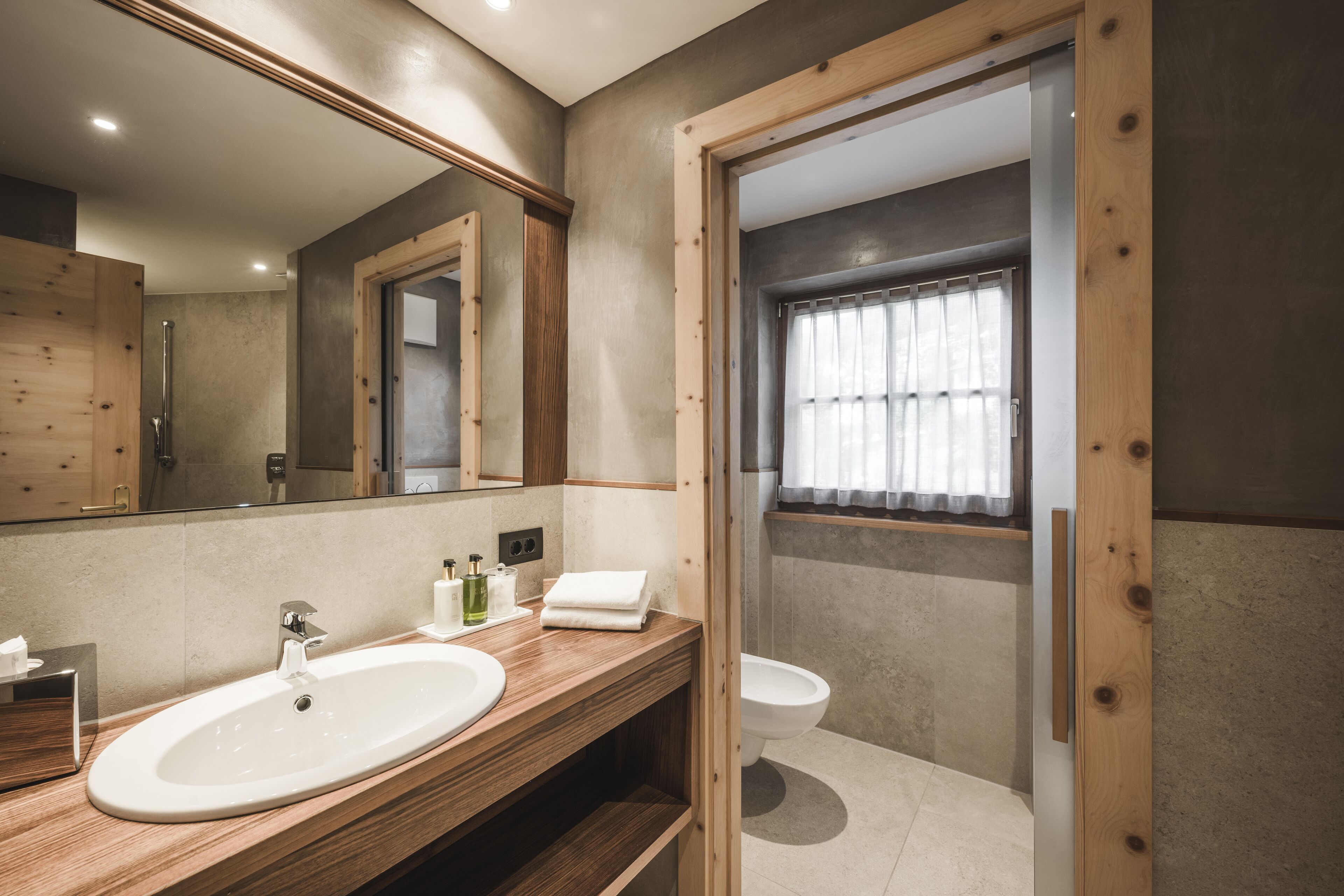 A modern bathroom with a wooden vanity, a large mirror, and a toilet.