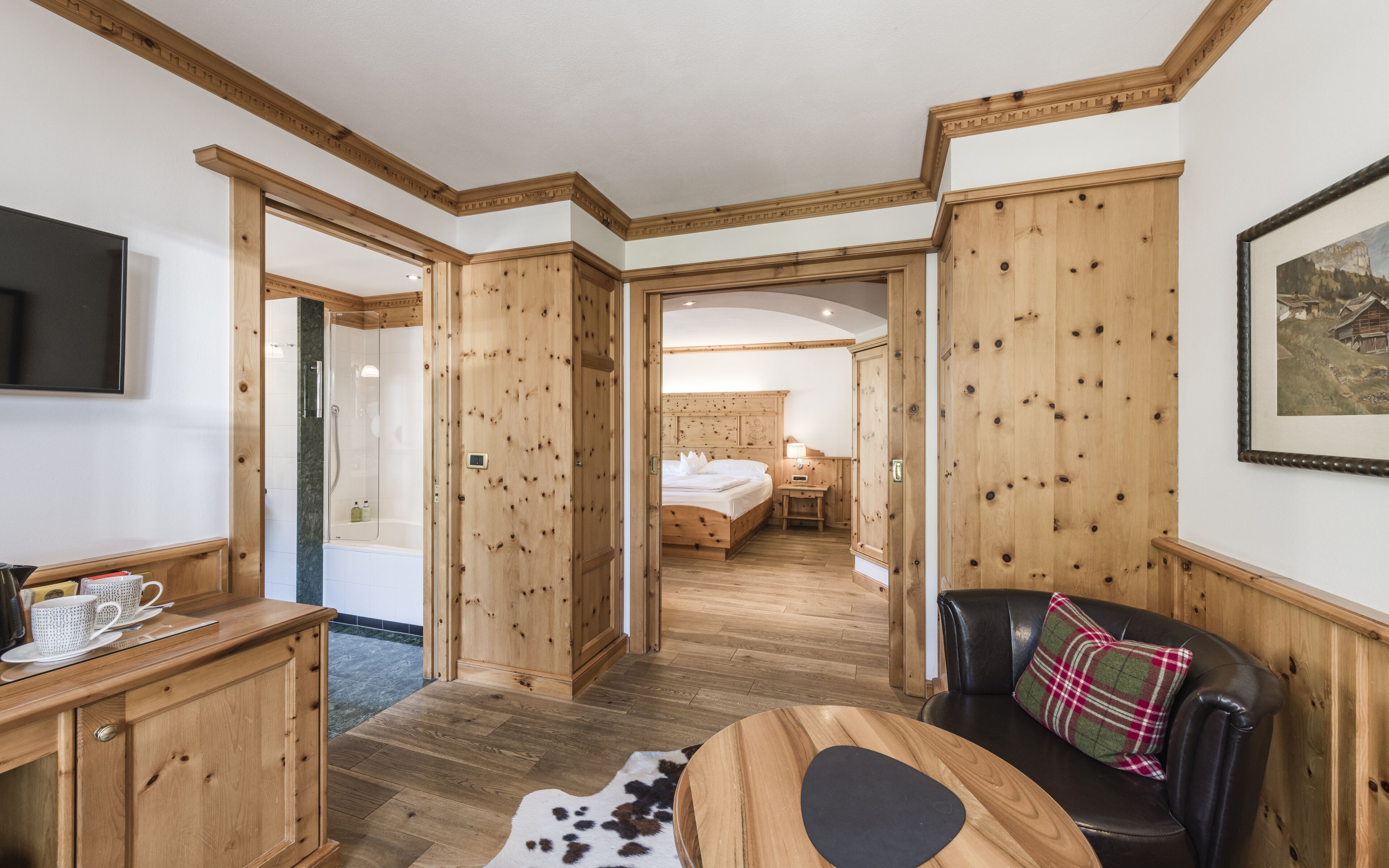 Una habitación con paredes de madera, una cama, un televisor, un escritorio y un sofá de cuero.