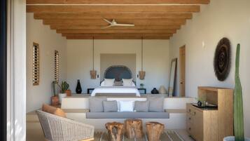 A modern bedroom with a large bed, a sofa, a wooden ceiling, and a cactus plant.