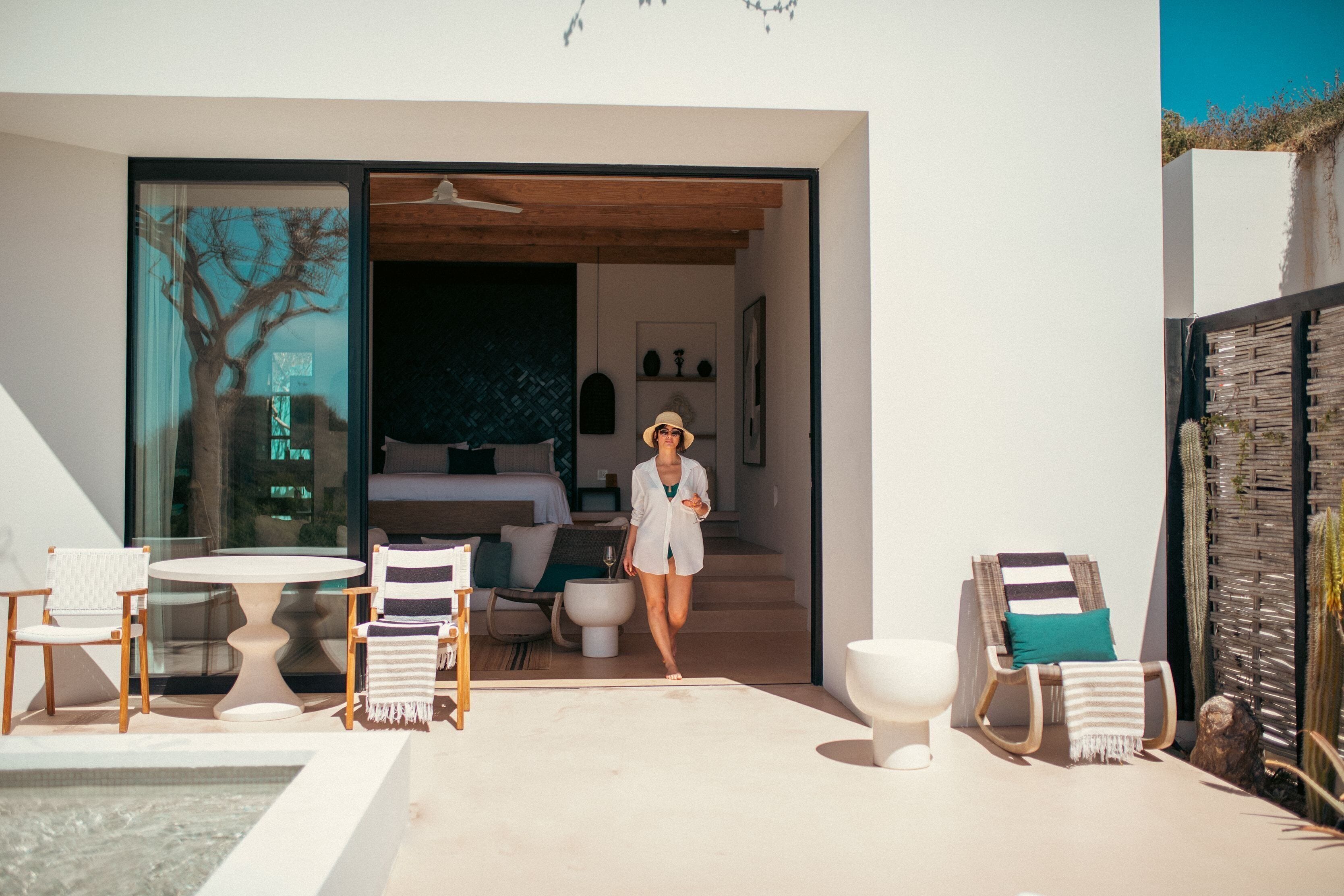 A modern outdoor living area with a pool, lounge chairs, and a staircase leading to an interior space.