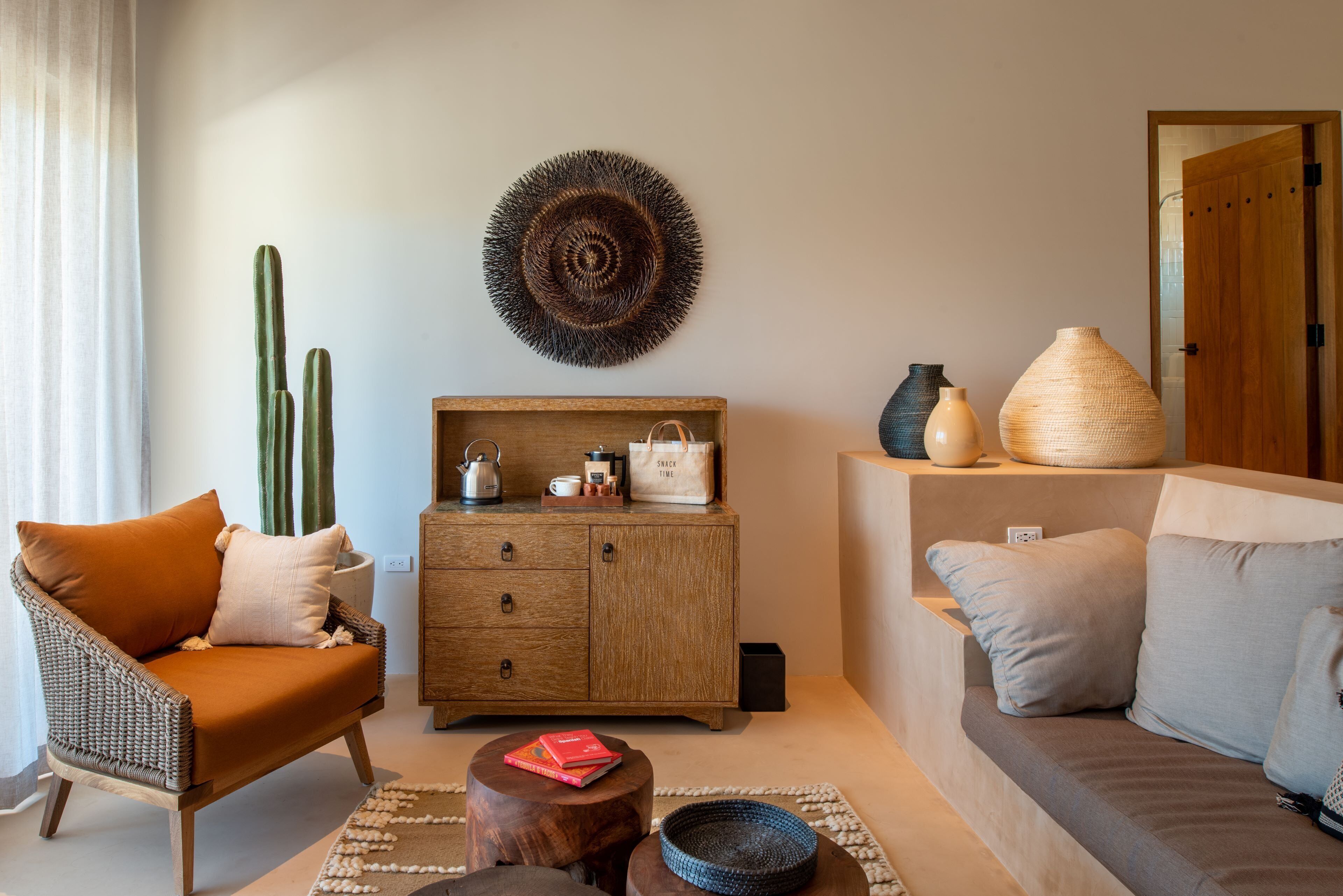 A living room with a wicker armchair, a wooden cabinet, a sofa, and a coffee table.