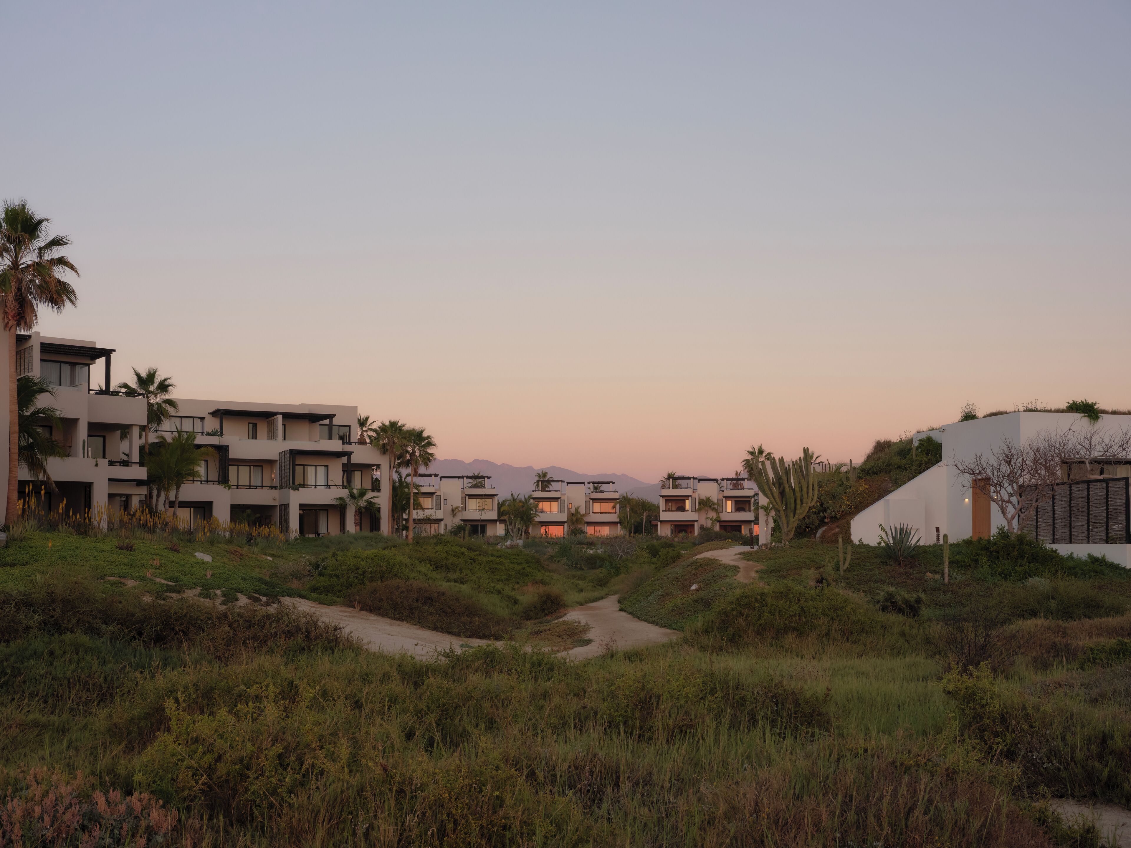 A modern resort with multiple-story buildings, a central pathway, and surrounding greenery.