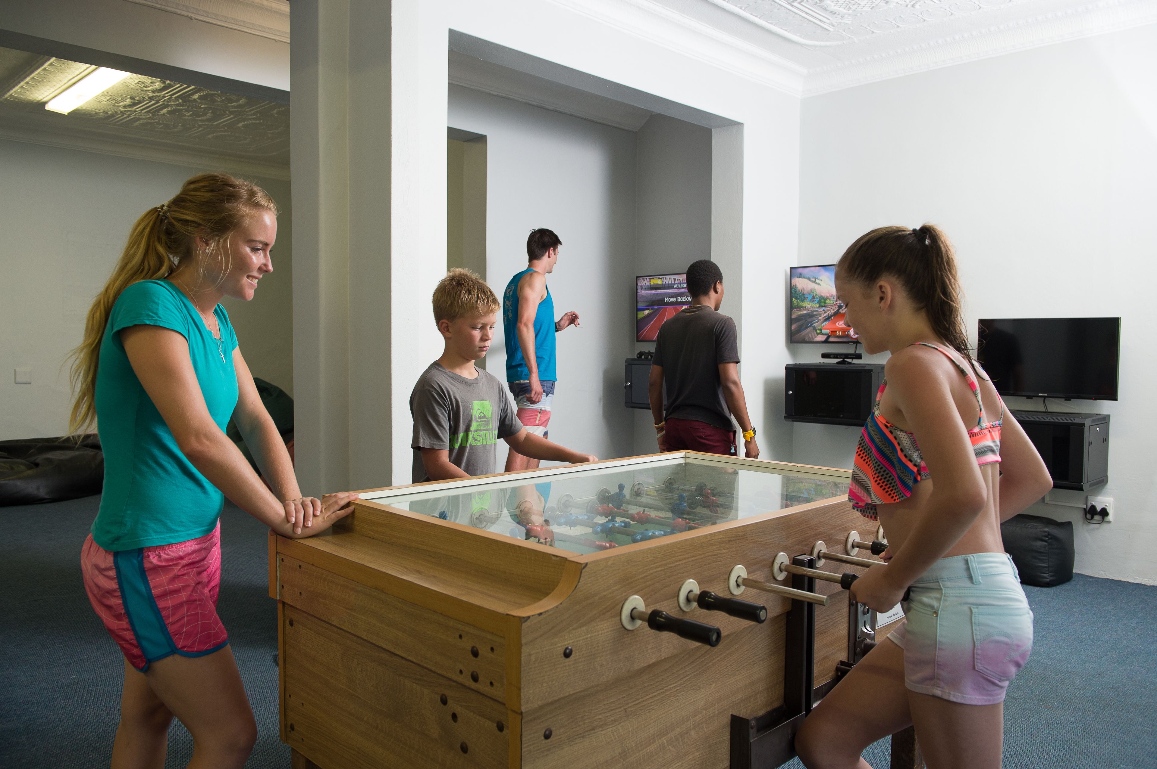 A room with a foosball table, a television, and a painting on the wall.