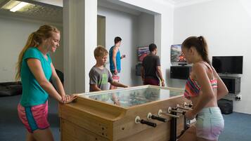 A room with a foosball table, a television, and a painting on the wall.