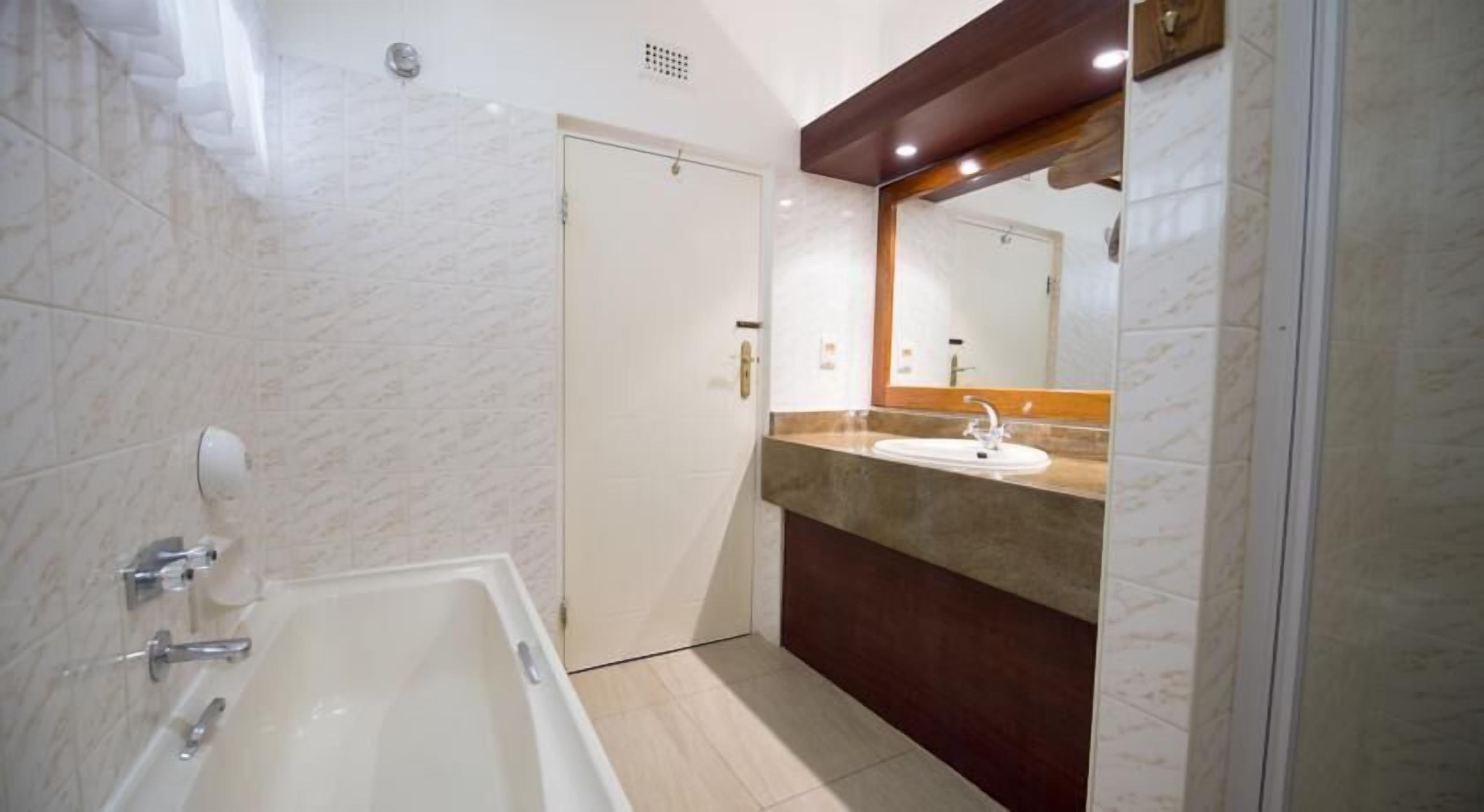 Une salle de bain moderne avec une baignoire, un lavabo et un miroir.
