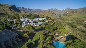 A resort with multiple buildings, a swimming pool, and a mountainous backdrop.