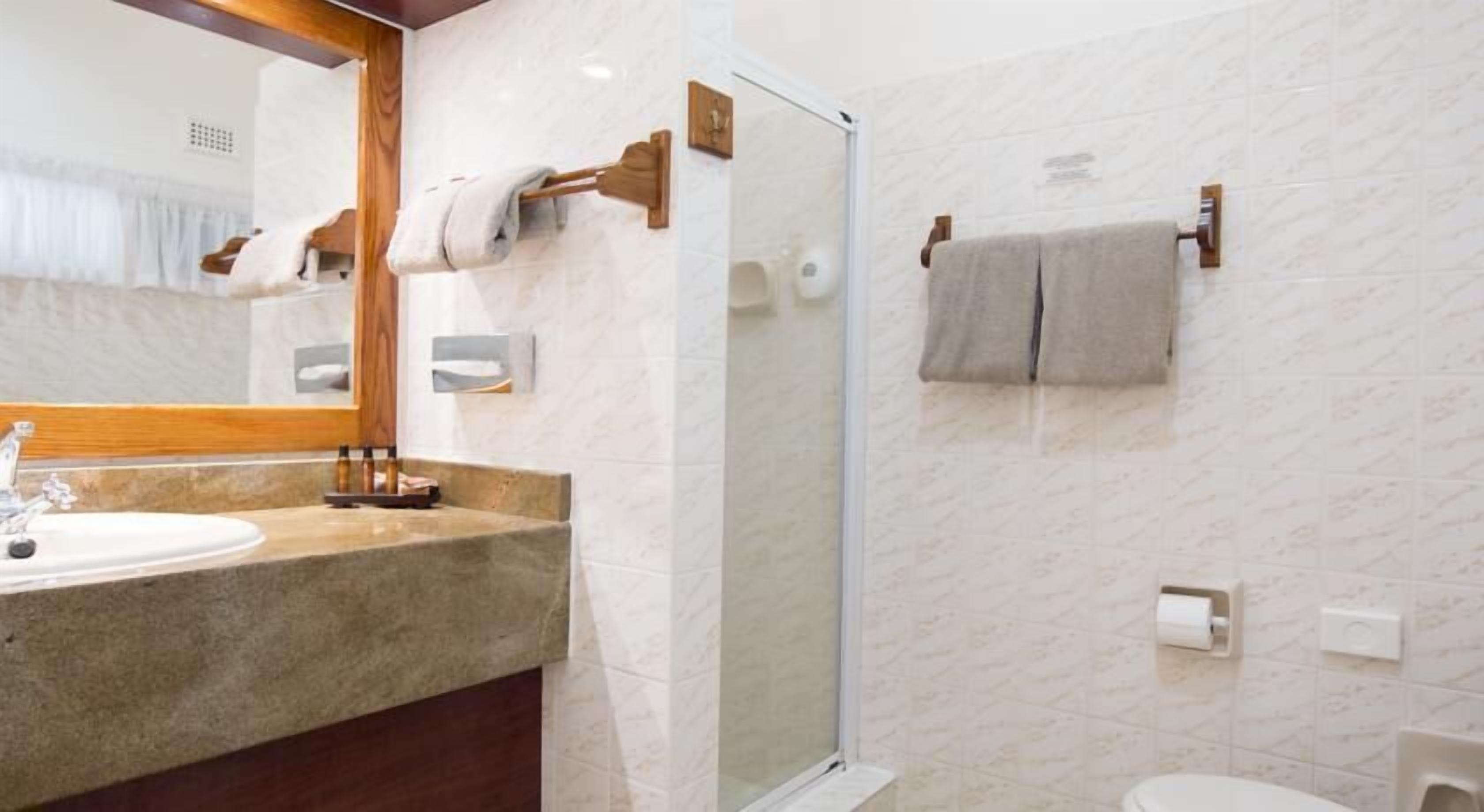 Une salle de bain avec un lavabo en marbre, une douche à parois de verre et des toilettes.