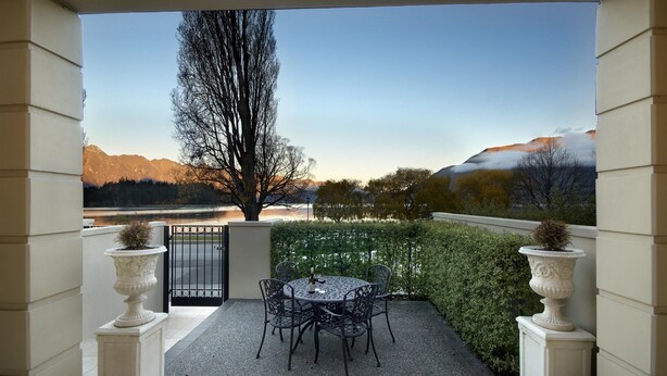 Une terrasse avec une table et des chaises, une vue sur les montagnes et un arbre.