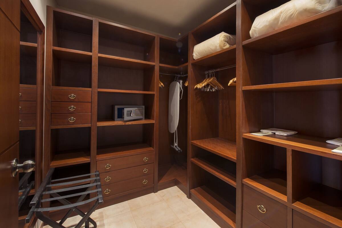 A walk-in closet with multiple shelves, drawers, and hanging space.