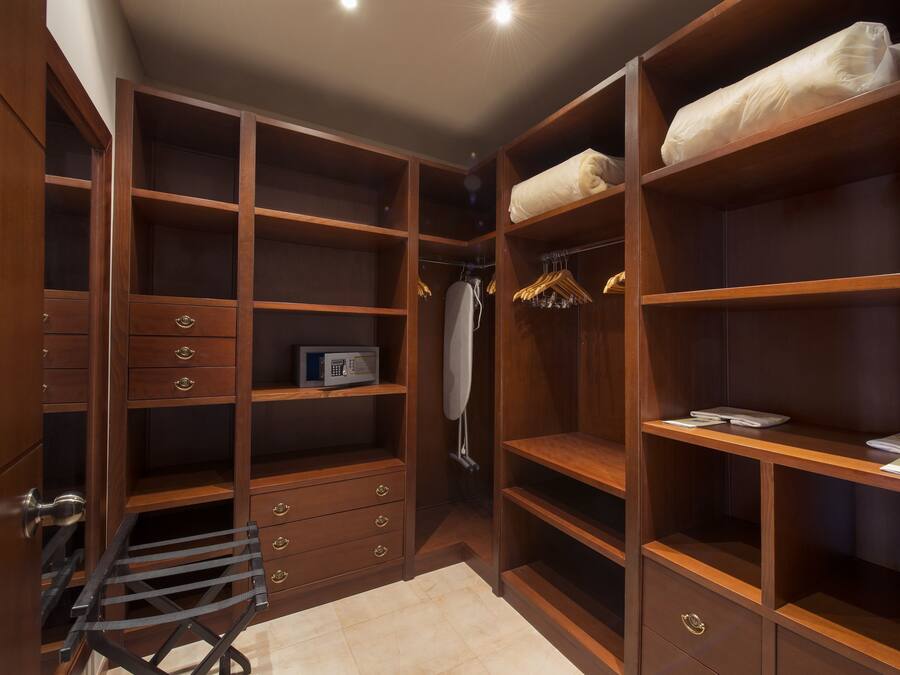 A walk-in closet with multiple shelves, drawers, and hanging space.