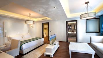 Una habitación de hotel moderna con una cama, un televisor sobre un mueble bajo, una mesa de centro blanca y un sofá.