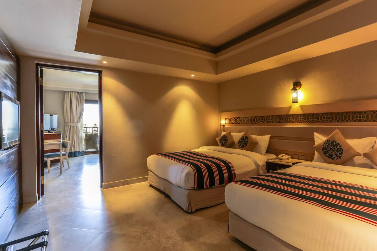 A hotel room with two beds, a desk, and a chair.