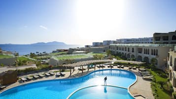 Ein Resort mit einem großen Pool, Liegestühlen und Blick auf das Meer.