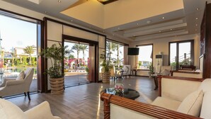 A spacious lobby with a wooden floor, large windows, and a seating area with a sofa and chairs. - SUNRISE Arabian Beach Resort (Sharm El Sheikh)
