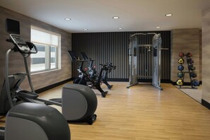 A gym with exercise equipment, a weight rack, and a window. - The Alexander, Autograph Collection (Indianapolis)
