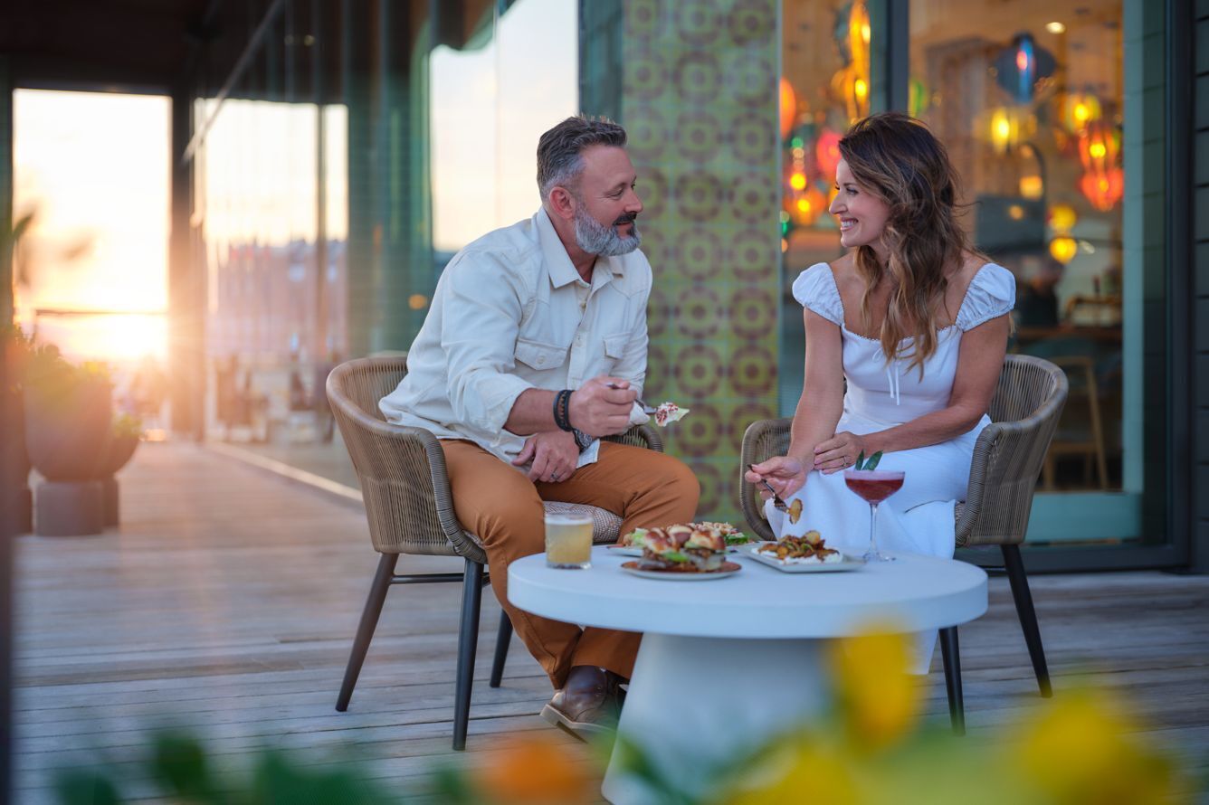 A couple dining at an outdoor table with a view of the sunset.