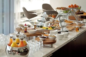 A buffet setup with various food items and beverages. - The Alexander, Autograph Collection (Indianapolis)