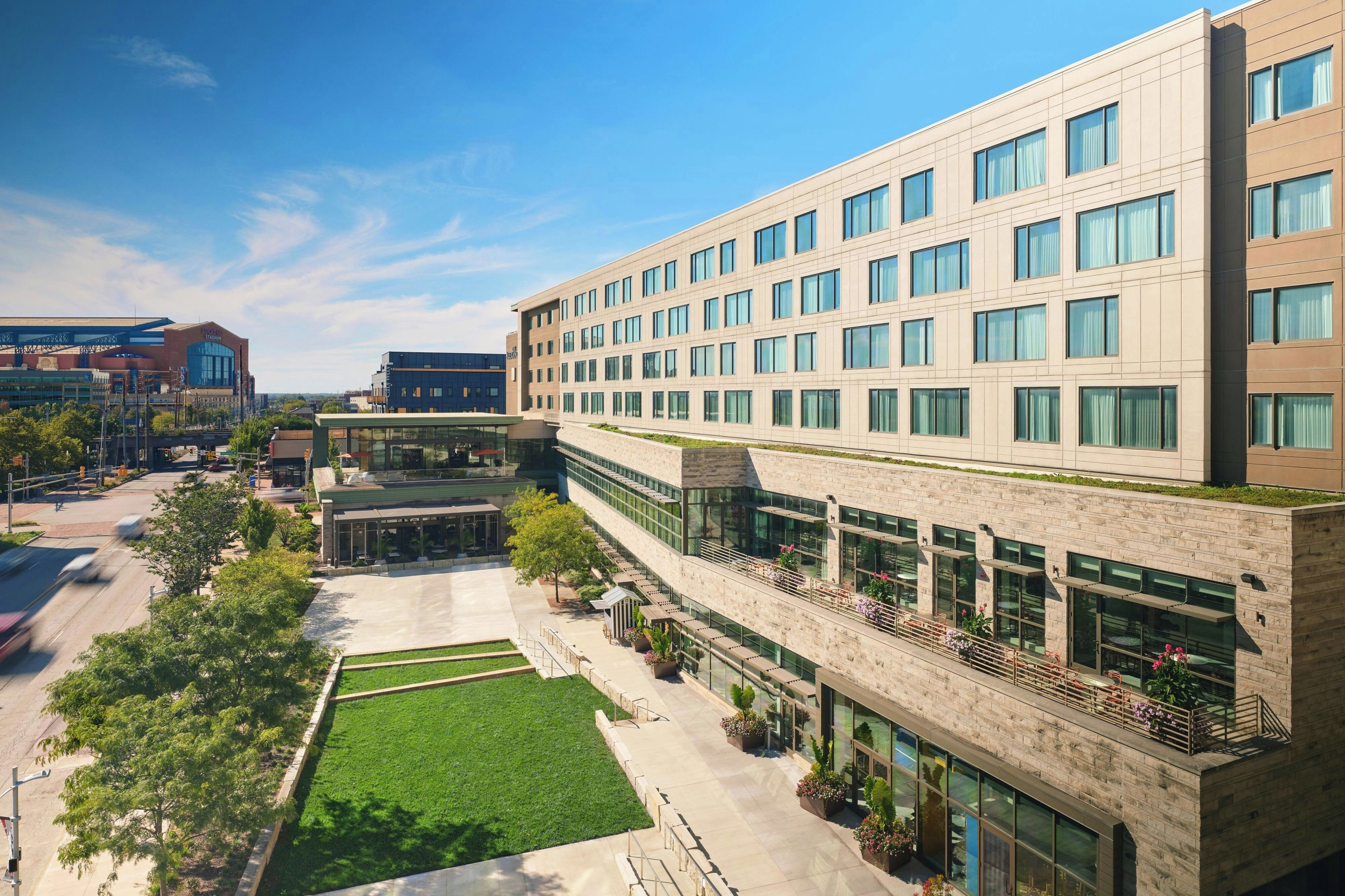 A modern building with multiple floors, large windows, and a green lawn in front.