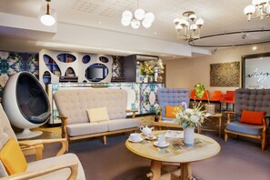 A modern hotel lobby with a sofa, chairs, a round table with tea set, and a TV. - Best Western Premier Why Hotel (Lille)