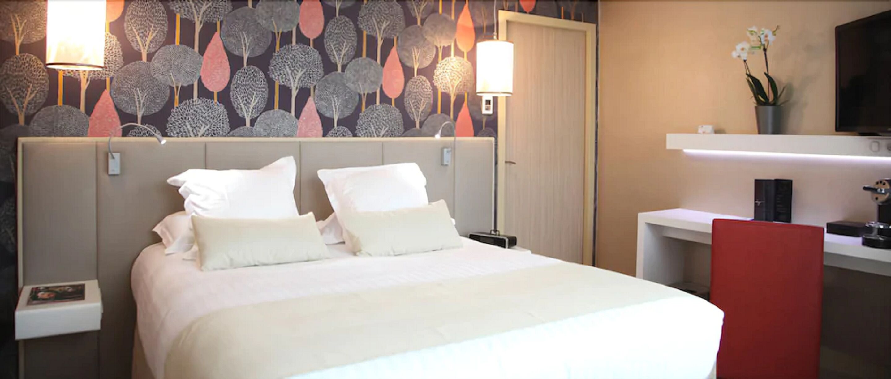 A hotel room with a bed, bedside tables, a desk, and a TV.