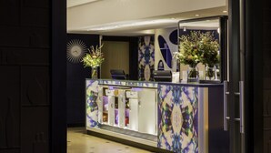 A reception area with a modern design, featuring a glass counter, decorative vases, and a clock on the wall. - Best Western Premier Why Hotel (Lille)