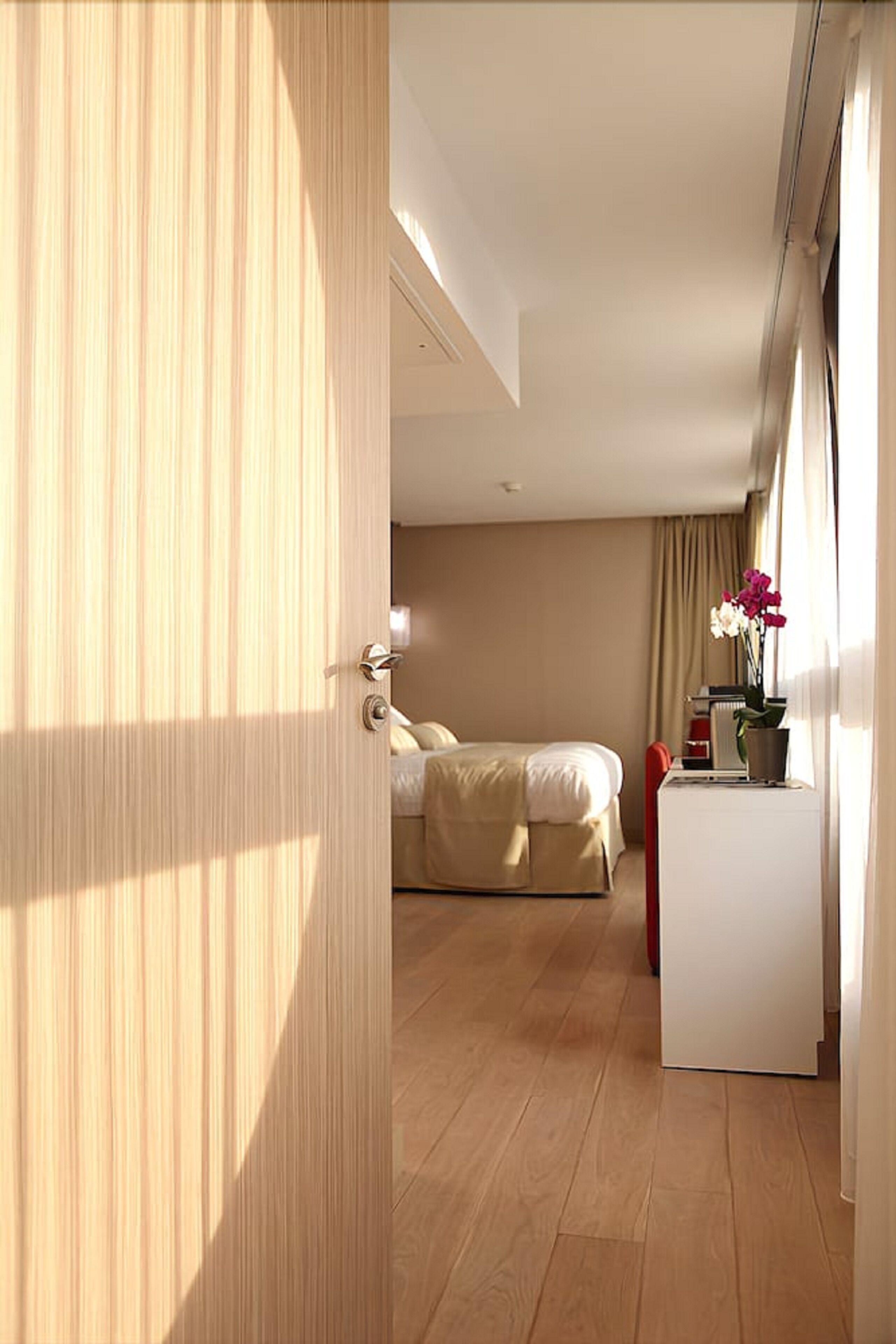 A hotel room with a bed, a desk, and a window with curtains.