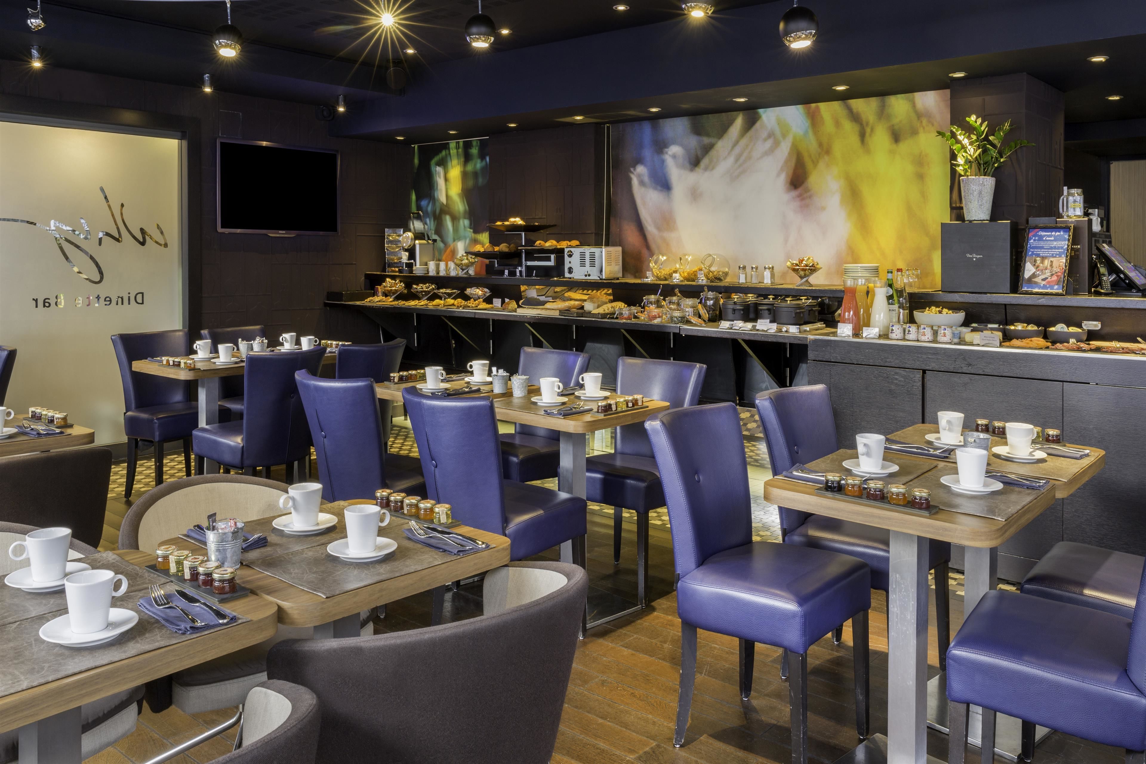 Un restaurant avec des tables dressées pour le service, un bar où l’on sert des boissons et un grand écran diffusant une image floue.