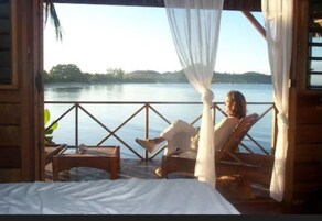 Una habitación con una cama, una mesa de madera y una silla frente a un lago.