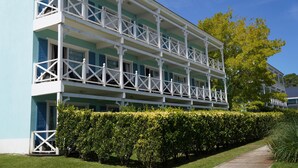 Un edificio a più piani con balconi, un prato curato e un siepe.