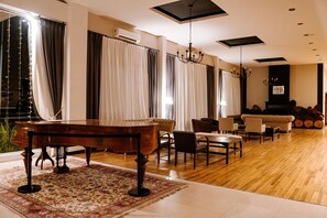A spacious living room with a grand piano, a sofa, and a chandelier. - Howard Johnson Hotel & Convention Center Madariaga Carilo (Carilo)