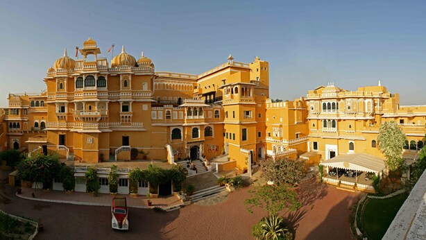 A large, ornate building with multiple levels and domes, surrounded by courtyards and pathways.