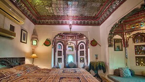 A room with a large ornate bed, a chandelier, and intricate wall decorations.