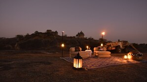 A campsite with a white tent, a lantern, and a table with a bowl of food.