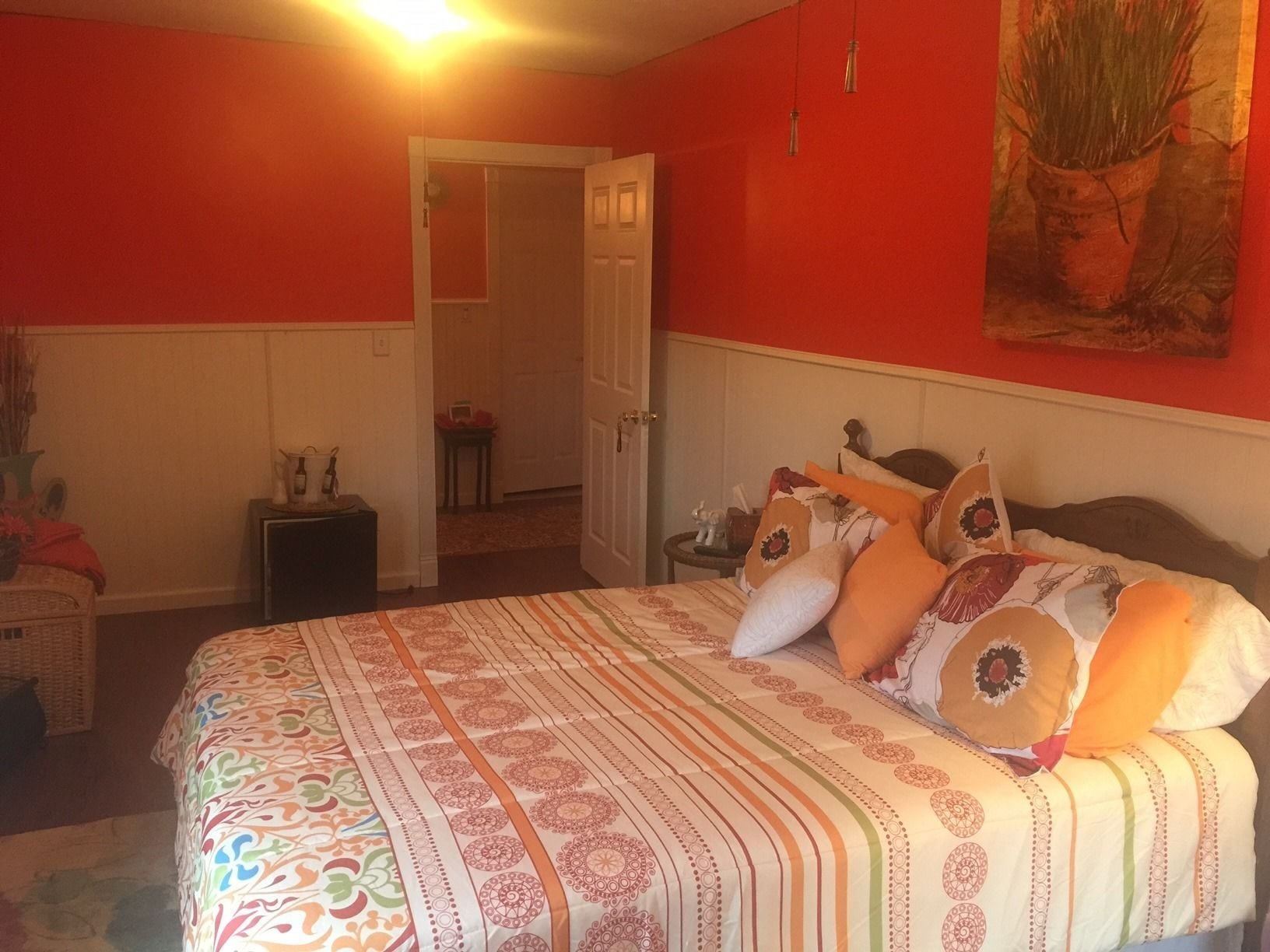 A bedroom with a bed, a nightstand, a chair, and a door leading to another room.