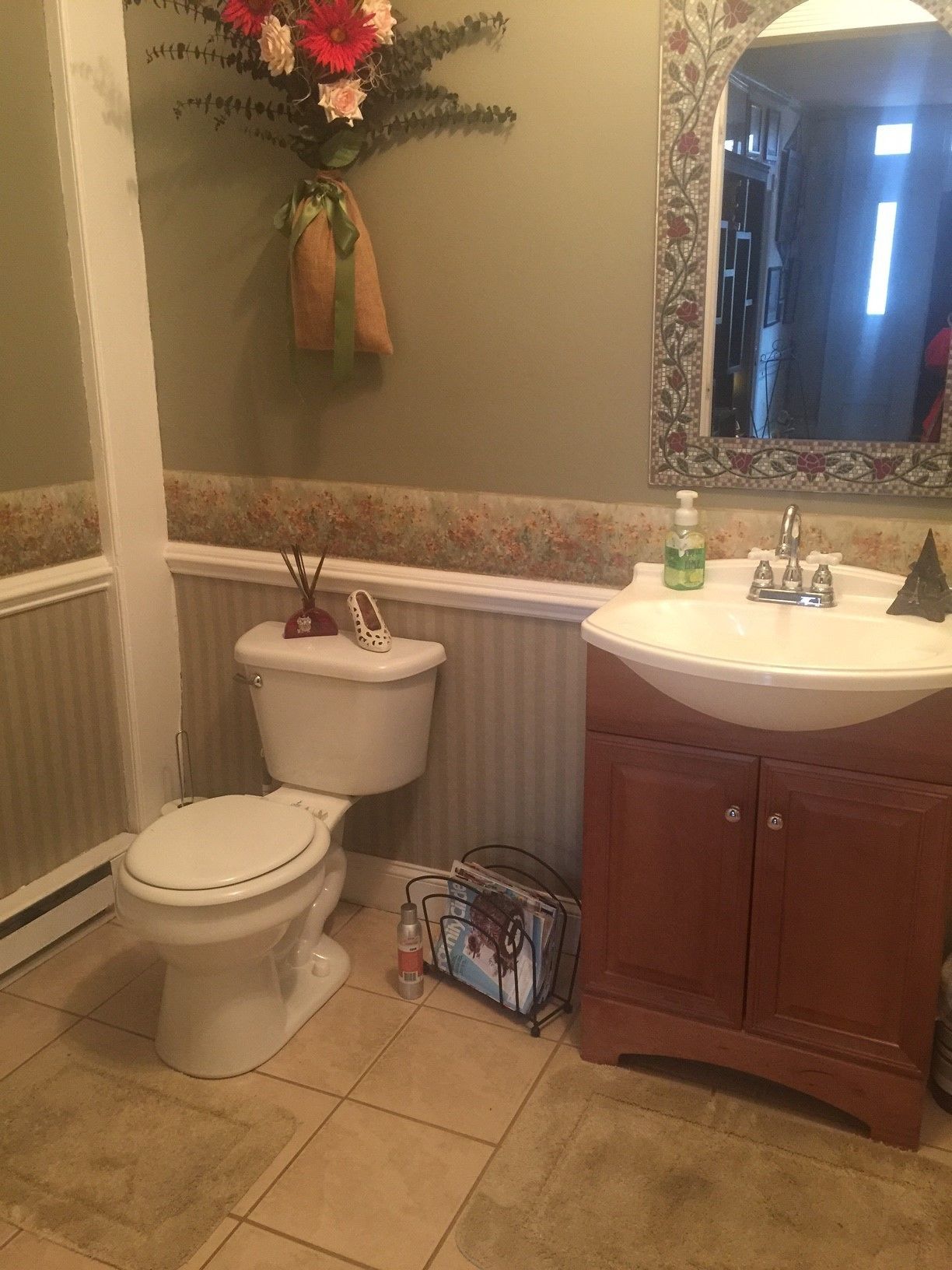 A bathroom with a toilet, sink, and mirror.