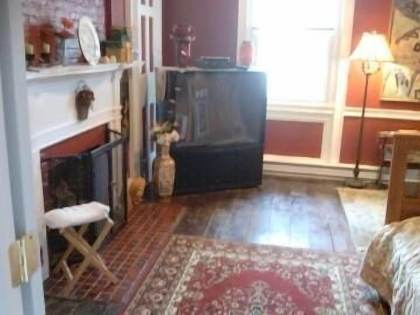 A room with a fireplace, a patterned rug, and a wooden bench.