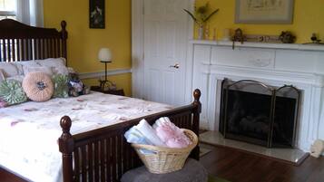 A bedroom with a wooden bed, a fireplace, and a yellow wall.