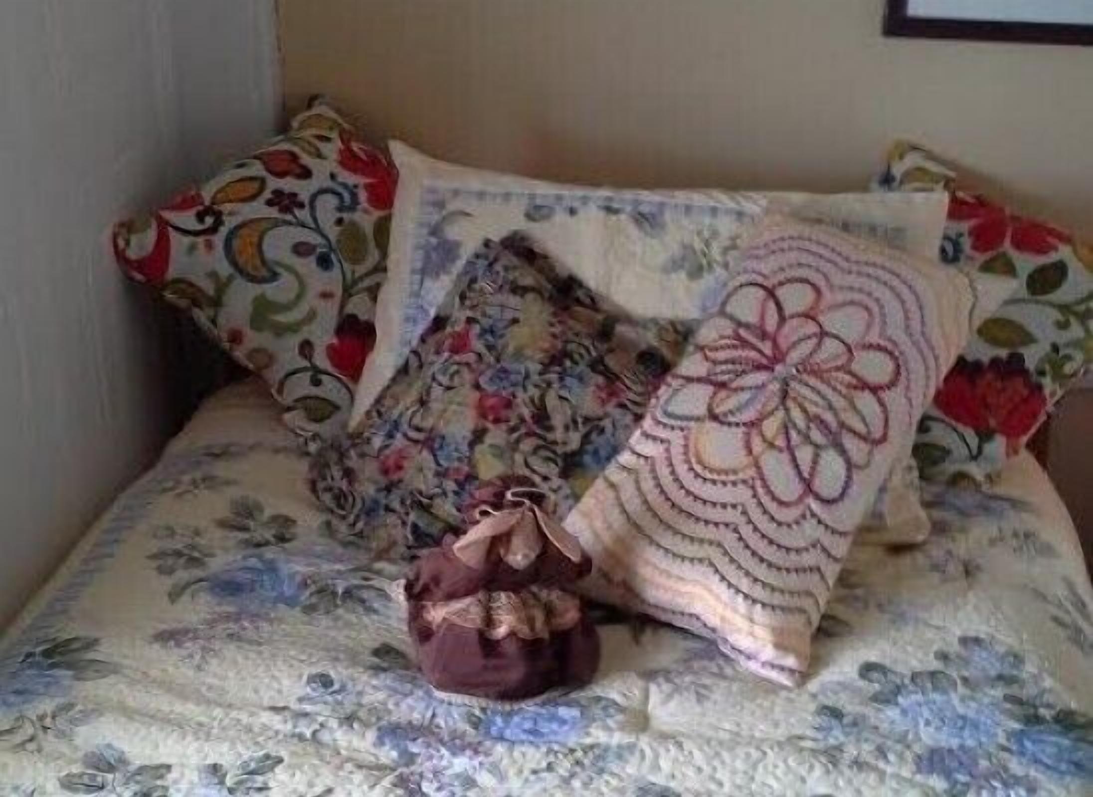 A bed with floral-patterned bedding and multiple decorative pillows.