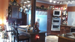 A kitchen with wooden cabinets, a central island, bar stools, a refrigerator, an oven, and a microwave.