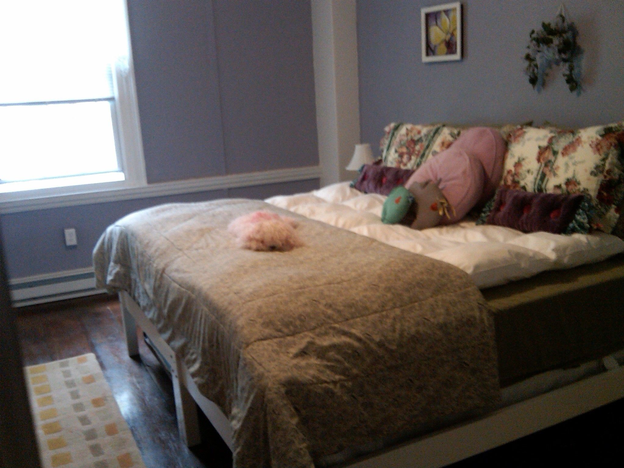 Quarto com cama, janela e parede com uma imagem.