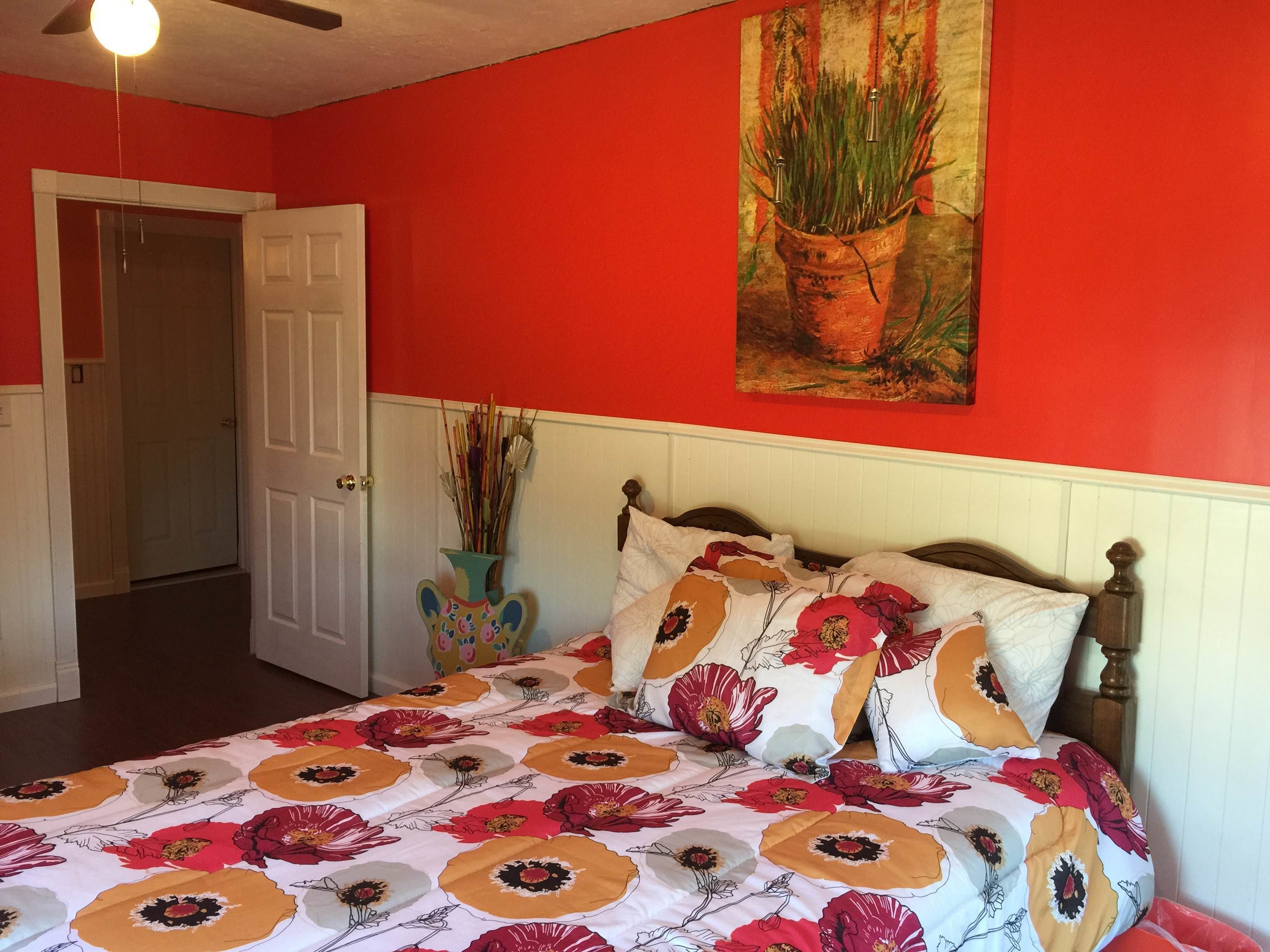 Une chambre à coucher avec un lit, une porte et un tableau au mur.